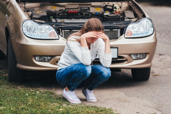 extended car warranty services woman upset next to broken car with open hood